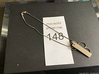 Full view of silver chain necklace with rectangular pendant marked 925.