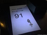 Single Pandora silver cross charm with crystals on a white background with MaxSold lot number card and black pouch beside.