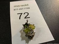 Front angled view of the pendant showing green and clear stones.