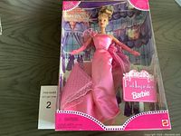 Front of box showing Barbie doll in pink satin gown with sheer polka-dot fabric and matching gloves, background of ballroom scene, Pink Inspiration Barbie label
