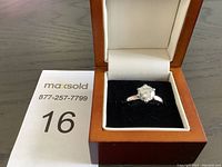 Front view of ring in box showing the clear round stone and silver band.