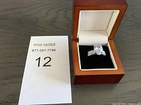 925 silver ring with large teardrop-shaped clear gemstone and baguette side stones in wooden display box.