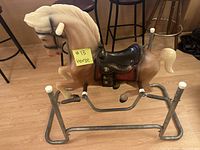 Plastic children's rocking horse mounted on metal spring frame with handles and footrests visible.