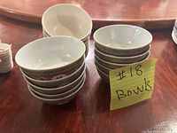 Stack of 6 plain plastic bowls and 10 ceramic bowls with a sticky note labeled '#18 Bowls' on a wooden table.