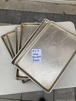 Six metal trays stacked, showing textured finish and rectangular shape.