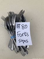 Photo showing a bundle of 50 stainless steel forks tied together with a blue rubber band and a note indicating quantity (#80 Forks 50pcs).