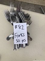A bundle of 50 standard metal forks with a note '#82 Forks 50 pcs'