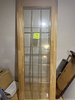 Front view of a new glass door with wood frame and subdivided glass panes in a 3x5 grid.