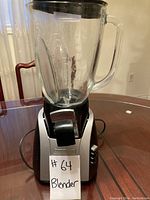 Front view of Hamilton Beach blender showing glass jar, lid, and handle placed on a wooden table.
