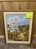 Full view of the framed tree painting with landscape background showing clear details of the artwork and frame.