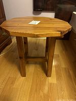 Front angle view showing the table's 11-sided polygonal top and wooden legs with support beams.