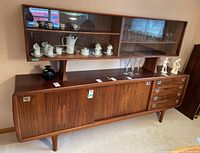 Full front view of assembled two-piece cabinet showing upper glass hutch and lower sideboard with drawers and doors.