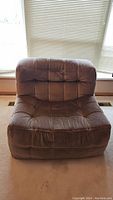 Front view of brown tufted chair showing seat and back upholstery