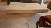Front angle of rectangular travertine coffee table on carpeted floor
