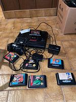 Full view of console, controller, adapter, RF switch and six cartridges on tile floor