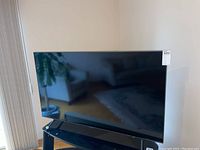 Front view of TV on black glass stand showing full screen and surroundings
