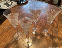 Four Waterford crystal champagne flutes standing on a wooden table, showing overall set.