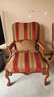 Front view of Ferretti custom upholstered armchair showing wood frame, claw feet, red and tan striped upholstery, and accent cushion