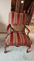Front view of the wood framed armchair showing upholstery and claw feet