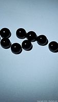 Close-up photo showing multiple round smooth polished black onyx beads, approximately 4mm size.