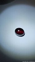 Oval cabochon Mozambique garnet gemstone showing lustrous deep red-purple color.