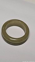 Photo of natural untreated green jade ring, showing the smooth polished surface and rounded shape.
