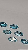 Six marquis cut natural blue Apatite gemstones shown on a light background emphasizing the paraiba blue color and clarity