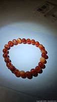 Clear photo of the red agate bead bracelet laid flat showing the round beads with natural color patterns