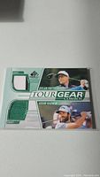Front view of the golf trading card featuring Adam Hadwin and Dylan Frittelli, each with a piece of fabric embedded as a memorabilia feature.