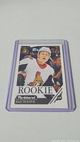 Photo of a Brady Tkachuk rookie hockey trading card from Parkhurst with player in Ottawa Senators jersey, encased in clear protective sleeve with purple border.