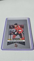 Photo of Brady Tkachuk rookie hockey card in protective plastic sleeve showing front with player image and team details.