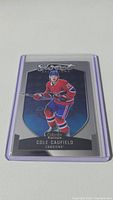 Front view of Cole Caufield rookie card in protective sleeve showing player in Montreal Canadiens uniform.