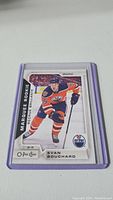 Photo of Evan Bouchard rookie O-Pee-Chee trading card in protective case showing player in Edmonton Oilers uniform.