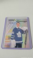 Front view of Joseph Woll rookie hockey card in protective sleeve showing clear holographic foil and number 122/749.