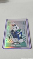 Photo of Quinn Hughes rookie hockey card from Parkhurst with holographic background and player in mid-action on ice.