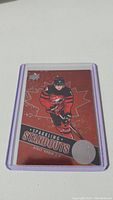 Photo of a Ridley Greig Sparkling Standouts rookie hockey card in a purple protective sleeve on a white surface.