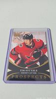 Photo of a Tim Stutzle rookie hockey card in a protective sleeve, showing the front design with the player in Ottawa Senators uniform and gold 'Prospects' text.