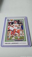 Photo of a 2021 Donruss rookie football card of Trevor Lawrence in a protective sleeve.