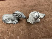 Two hand carved soapstone figurines of an Arctic seal and a fawn on a brown textured surface.