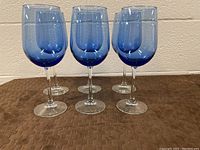 Six blue glass wine glasses arranged in two rows, showing the color, shape, and clear stems.