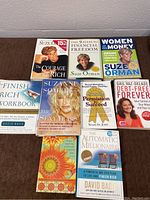 Nine financial self-help books arranged on a brown surface showing front cover titles and authors