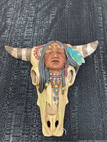 Front view of the bull skull with Native American Indian head sculpture, showing detailed paint and braids.