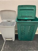 Grey plastic pedal trash can with open hinged lid, showing foot pedal mechanism.