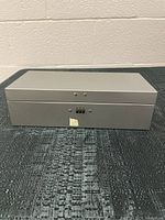 Front view of the gray metal lock box with combination lock, closed.