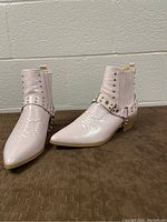 Front angled view of pink metallic pointy toe ankle cowboy boots showing studded strap detail and block heel