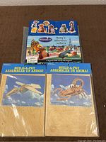 Photo showing Ratatouille magnetic book with characters and two unopened Build-A-Pet wooden puzzles (spaceship and scorpion).