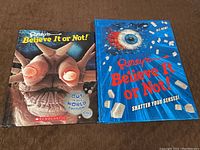 Two Ripley's Believe It Or Not books together on a brown surface.