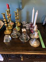 Overall lot showing brass candle holders, pewter holders with t-candles, clear glass votive holders and a modern glass single candle holder.