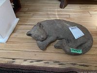 Full view of the sleeping cat statue casting on a wooden floor showing overall shape and size.