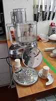 Photo of the Cuisinart MP-14C food processor base unit with 4 stainless steel attachments on a kitchen countertop.